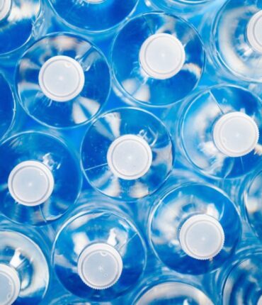 High angle view of plastic water bottles in a row. Concept of industrial production, recycling, disposal of waste, and environmental conservation.